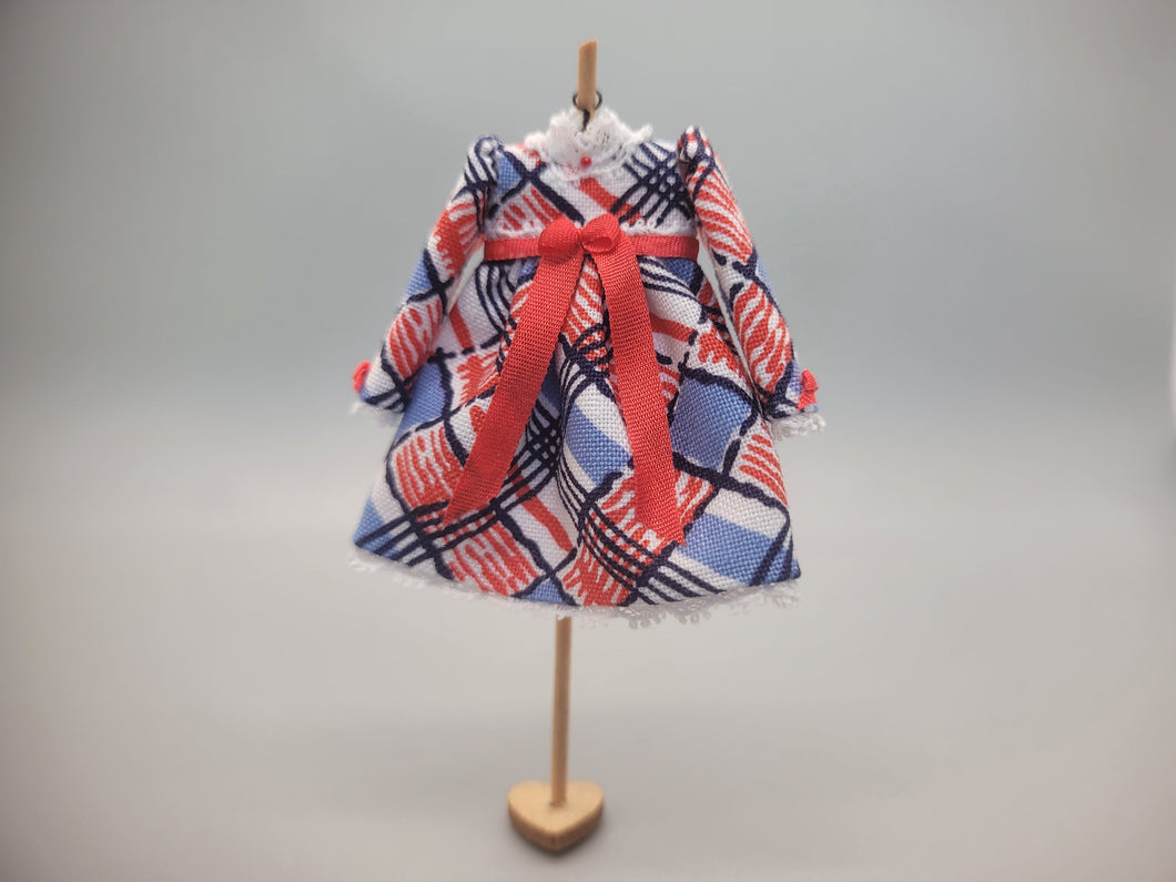Red, White, and Blue Design on Dress with Red Bow on Wooden Display – by Cheryl Warder