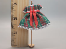 Load image into Gallery viewer, Green and Red Plaid Dress with Red Bow on Wooden Display – by Cheryl Warder
