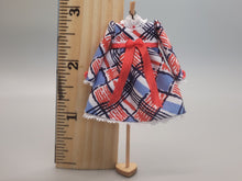 Load image into Gallery viewer, Red, White, and Blue Design on Dress with Red Bow on Wooden Display – by Cheryl Warder
